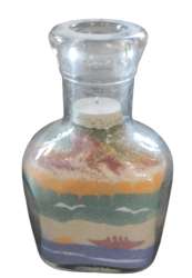 Layers of colored sand bottle, creating a beach landscape with a boat and birds.