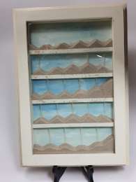 Sand game under glass in a white wooden frame