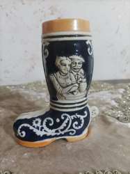 A shoe-shaped vase made of white and blue porcelain with a man’s head on it