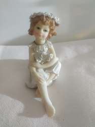 A sitting girl statue made of hand-carved resin in white and brown